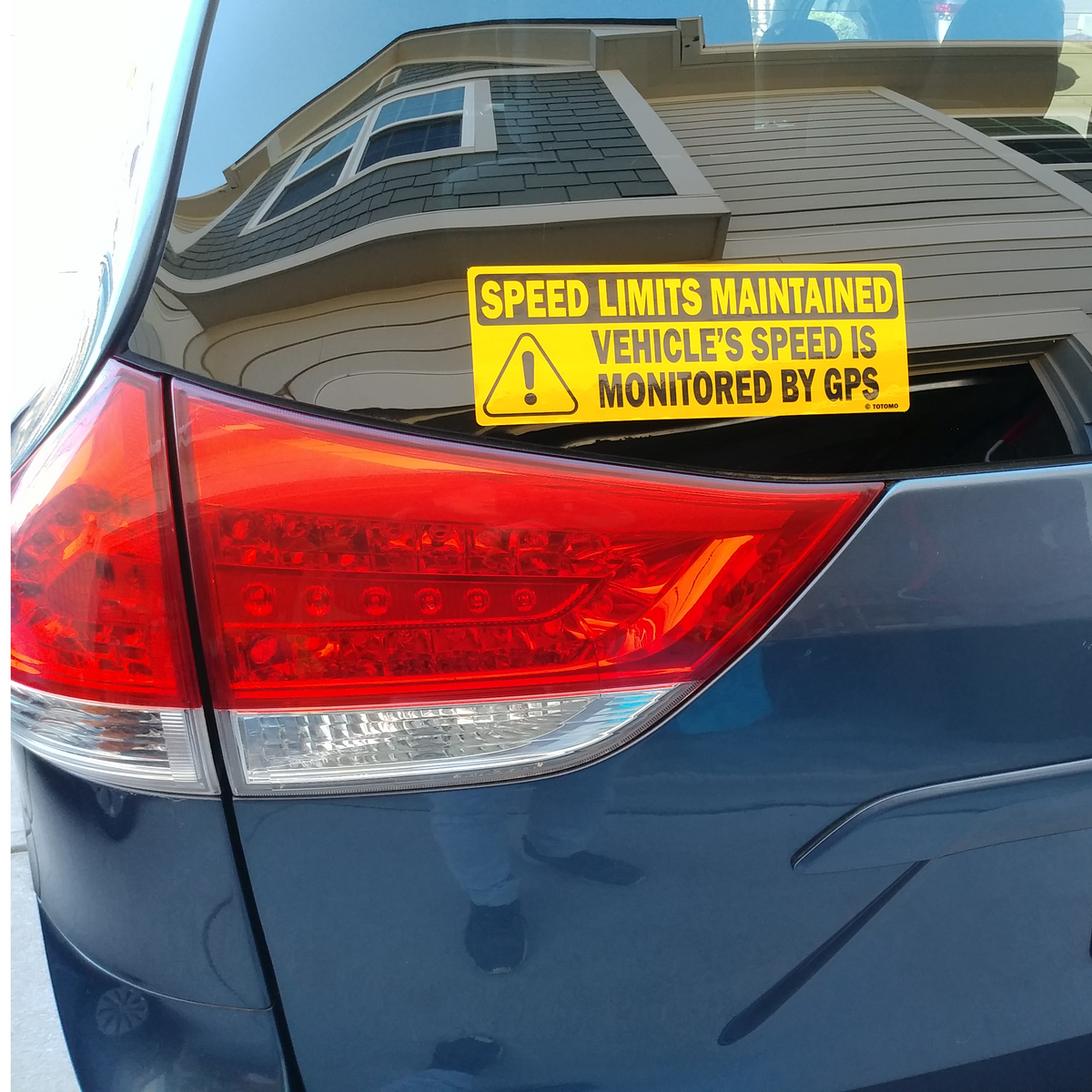 TOTOMO close view of a black-letter GPS speed monitored sign on a blue vehicle