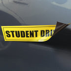 TOTOMO corner of a Student Driver magnet lifted from a vehicle panel